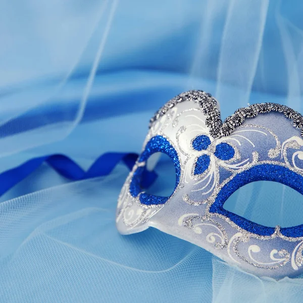 Imagem de delicada máscara venetian elegante sobre seda azul e fundo de tecido de tule . — Fotografia de Stock