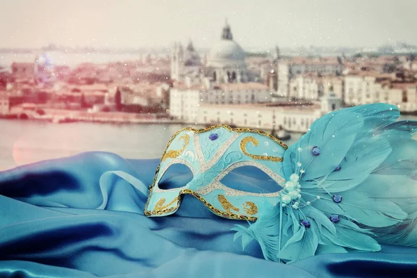 Afbeelding van elegante Venetiaanse masker op zijde stof voor onscherpe achtergrond van Venetië. — Stockfoto