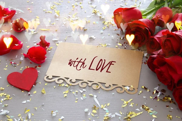 Fond de Saint-Valentin. Beau bouquet de roses à côté de la lettre avec texte AVEC AMOUR sur table en bois . — Photo
