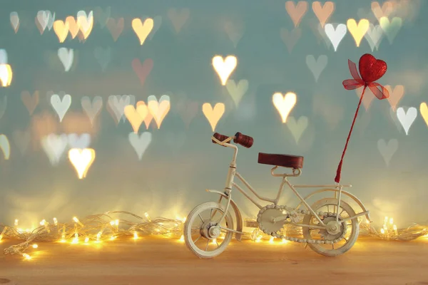 Dia dos Namorados fundo romântico com branco brinquedo de bicicleta vintage e brilho coração vermelho sobre ele sobre mesa de madeira . — Fotografia de Stock