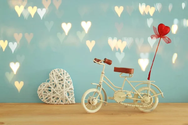 Dia dos Namorados fundo romântico com branco brinquedo de bicicleta vintage e brilho coração vermelho sobre ele sobre mesa de madeira . — Fotografia de Stock