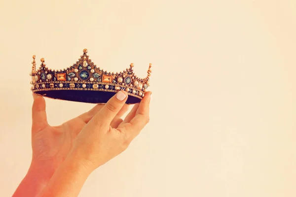 Main de femme tenant une couronne pour montrer la victoire ou gagner la première place. Fond blanc. Espace de copie. Isolé . — Photo