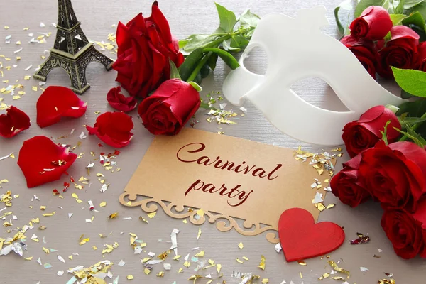 Wizerunek eleganckiej weneckiej masce i czerwone róże na drewnianym stole — Zdjęcie stockowe