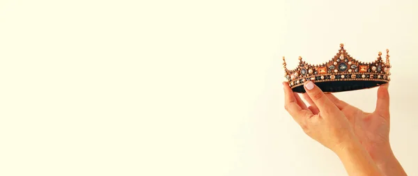 Main de femme tenant une couronne pour montrer la victoire ou gagner la première place. Fond blanc. Espace de copie. Isolé . — Photo