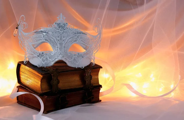 Bild einer zarten und eleganten weißen venezianischen Maske über alten Büchern vor Tüll-Hintergrund. — Stockfoto