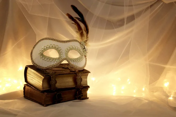 Образ елегантної венеціанської маски над старовинними старими книгами перед фоном тюлю . — стокове фото