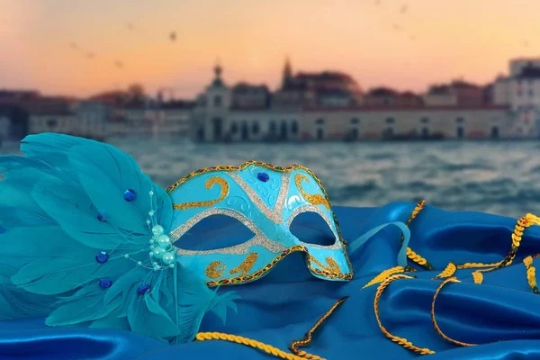 Image of elegant venetian mask on silk fabric in front of blurry