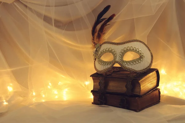 Image of elegant venetian mask over vintage old books in front of tulle background. — Stock Photo, Image