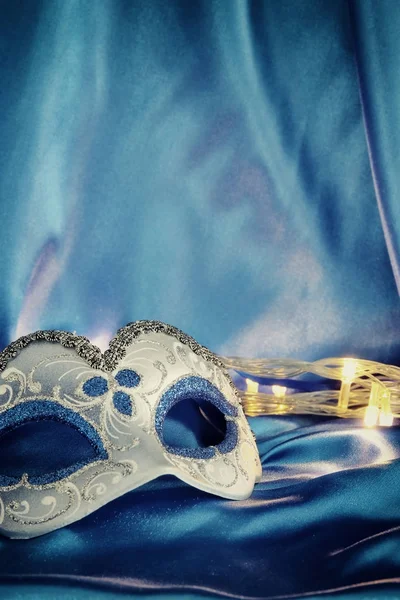 Imagem de elegante máscara veneziana sobre fundo de seda azul . — Fotografia de Stock