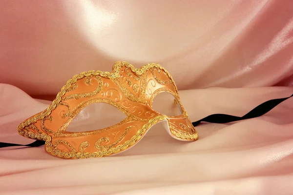 Image of elegant venetian mask over gold silk background.