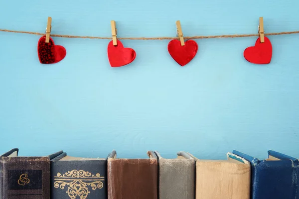 Fond de Saint-Valentin. Coeurs rouges suspendus à la corde et vieux livres . — Photo