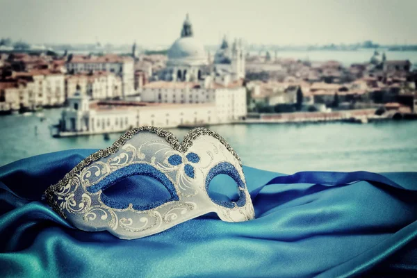 Imagem de máscara veneziana elegante em tecido de seda na frente de borrão — Fotografia de Stock