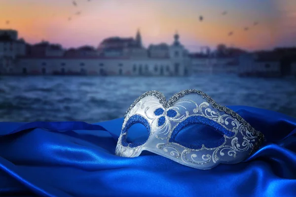 Image d'un élégant masque vénitien sur un tissu de soie devant un arrière-plan flou de Venise — Photo
