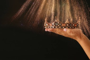Glitter kaplaması ile siyah arka plan üzerine bir taç Haritayı zafer ya da kazanan ilk yer tutan kadının el.