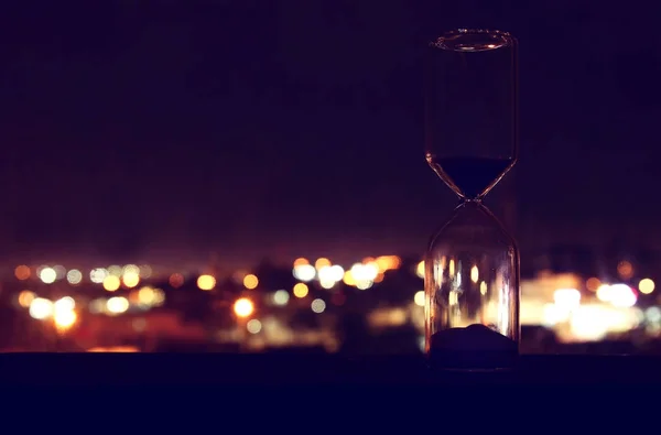비즈니스 마감에 대 한 개념을 전달 하는 시간으로 bokeh 도시의 불빛에 모래 시계. — 스톡 사진