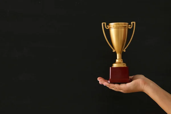 Low key image of a woman holding a trophy cup over dark background. — Stock Photo, Image