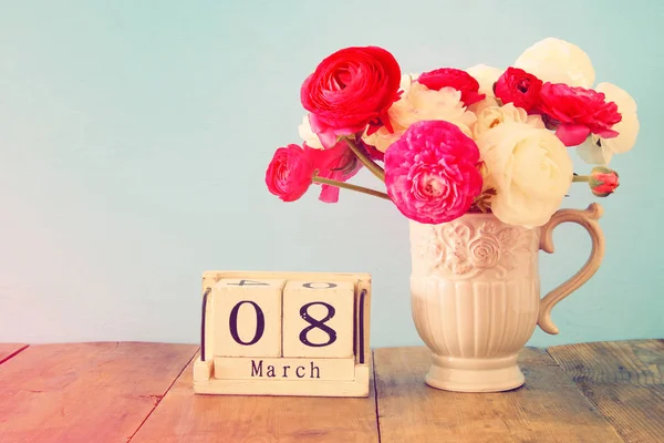 Концепция Международного женского дня с красивыми цветами в вазе и датой на деревянном столе . — стоковое фото