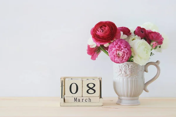 Concepto de día internacional de las mujeres con hermosas flores en el jarrón y la fecha en la mesa de madera . — Foto de Stock