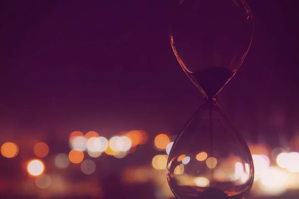 Hourglass peste luminile orașului Bokeh ca concept de trecere a timpului pentru termenul limită de afaceri . — Fotografie, imagine de stoc