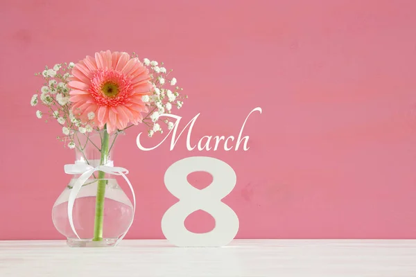 Image of International women day concept with beautiful flower in the vase on wooden table.