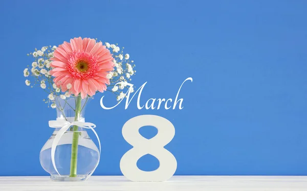 Imagen del concepto de día internacional de la mujer con hermosa flor en el jarrón en la mesa de madera . — Foto de Stock