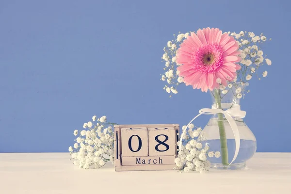 Imagen del concepto de día internacional de la mujer con hermosa flor en el jarrón en la mesa de madera . — Foto de Stock