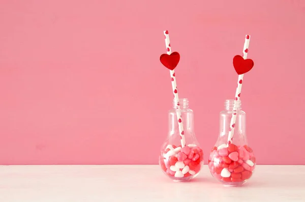 Aftelkalender voor Valentijnsdag romantische achtergrond met plastic lampje met hart vorm zoete snoepjes en feestelijke verlichting op tafel. — Stockfoto