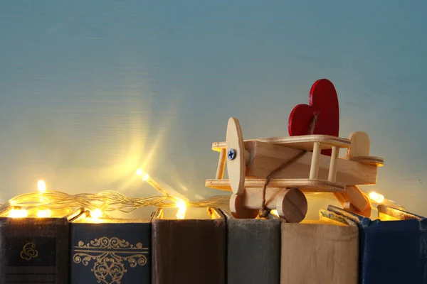 Den svatého Valentýna pozadí. Dřevěná hračka letadlo se srdcem přes staré knihy. — Stock fotografie