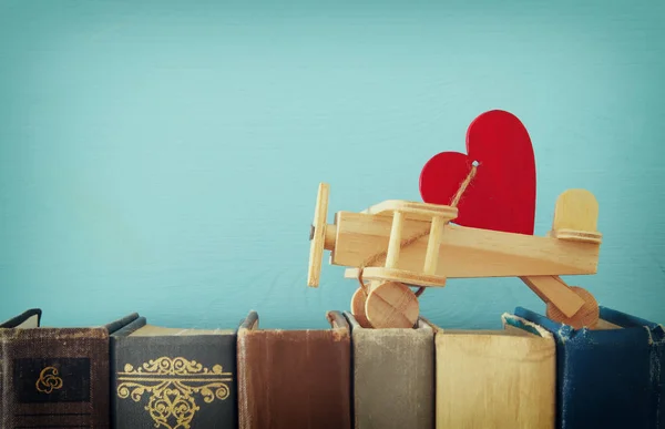 Valentine's day background. Wooden toy plane with heart over old books. — Stock Photo, Image
