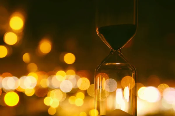 Hourglass over bokeh city lights as time passing concept for business deadline. — Stock Photo, Image