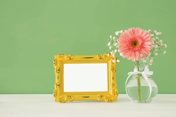 Imagen de hermoso ramo de flores de primavera junto al marco de fotos vintage en blanco en la mesa de madera. Para la fotografía maqueta de montaje . — Foto de Stock