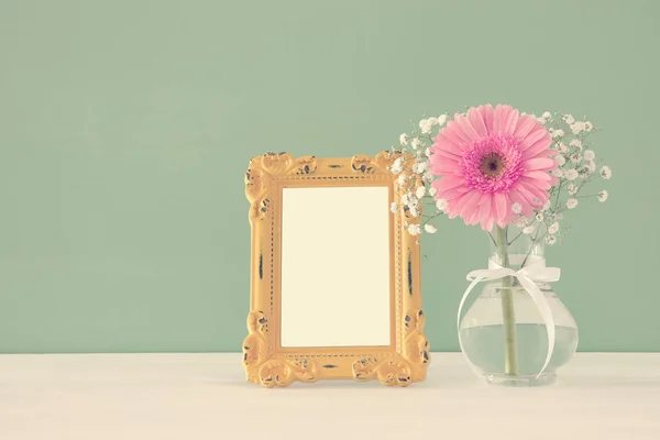 Image de beau bouquet de fleurs printanières à côté du cadre photo vintage vierge sur une table en bois. Pour la photographie maquette montage . — Photo