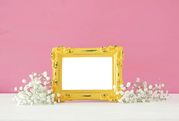 Immagine di bel mazzo di fiori primaverili accanto a cornice fotografica vintage vuota su tavolo di legno. Per la fotografia fingere montaggio . — Foto Stock