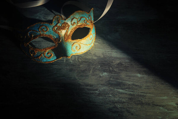 Изображение элегантной сине-золотой венецианской, марди-гра маски на темном фоне

