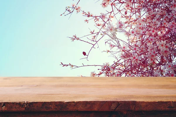 Table rustique en bois devant un arbre en fleurs de cerisier de printemps. image filtrée vintage. affichage du produit et concept de pique-nique . — Photo