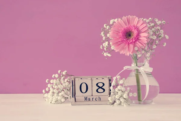 Imagen del concepto del Día Internacional de la Mujer con una hermosa flor en el jarrón sobre una mesa de madera . — Foto de Stock