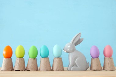 Renkli arka plan üzerinde renkli yumurta yanında sevimli tavşan.