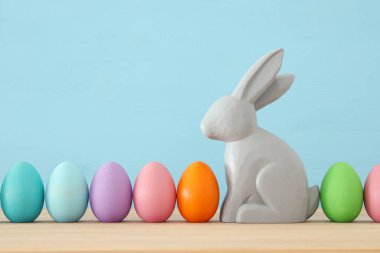 Renkli arka plan üzerinde renkli yumurta yanında sevimli tavşan.
