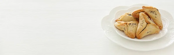 Концепція святкування Пурим (єврейське карнавальне свято). Традиційне печиво з шинки над білим столом . — стокове фото