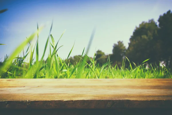 Empty rustic table in front of low angle view of fresh grass. product display and picnic concept. — Stock Photo, Image