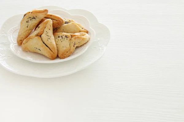 Purim oslava koncepce (židovský karneval dovolená). Soubory cookie tradiční hamantaschen bílý stůl. — Stock fotografie