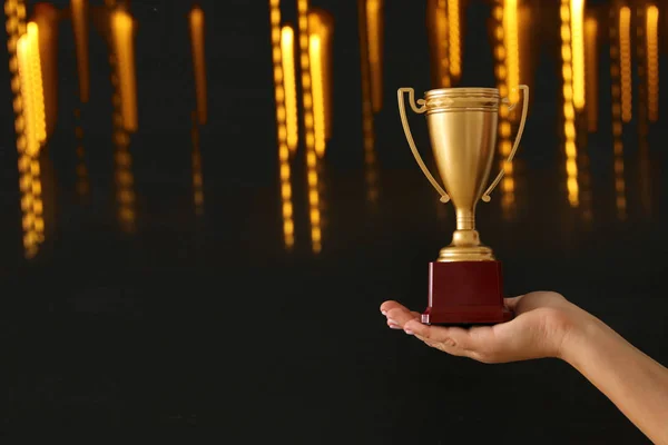 Low key image of a woman holding a trophy cup over dark background. — Stock Photo, Image