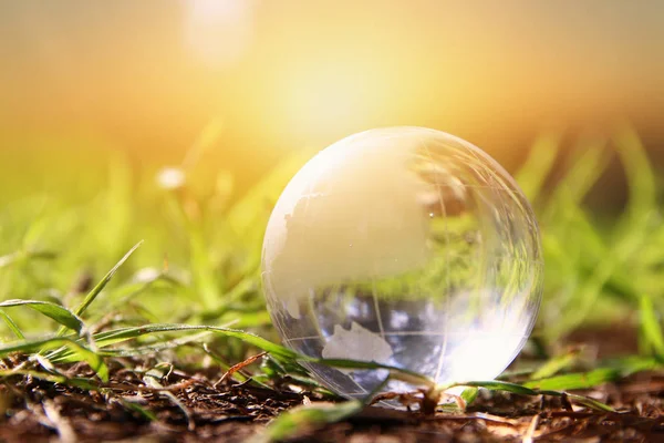 Petit globe de cristal à angle bas dans l'herbe. concept de voyage et enjeux mondiaux . — Photo