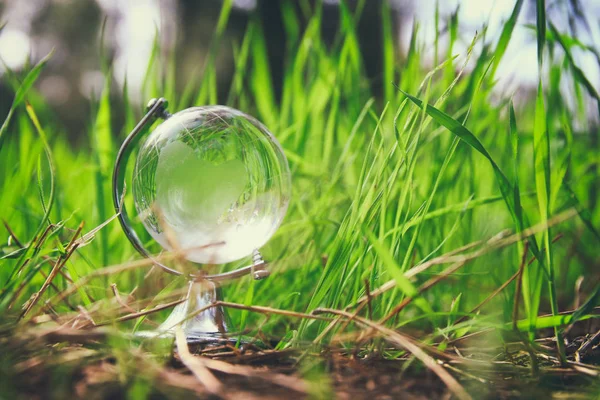 Petit globe de cristal à angle bas dans l'herbe. concept de voyage et enjeux mondiaux . — Photo