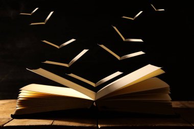 açık antika kitap sayfaları uçan ile ahşap masa üzerinde görüntü.