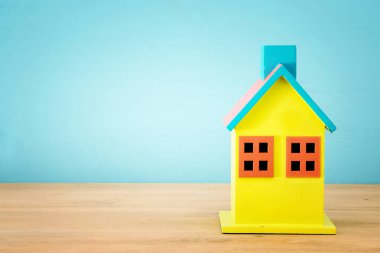 Ahşap renkli ev modeli üzerinde mavi arka plan görüntüsü. Emlak kavramı.