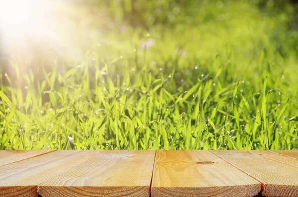 Tom rustika bordet framför låg vinkel syn på färskt gräs. produkten visar och picknick koncept. — Stockfoto