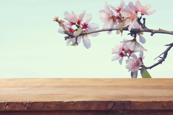 Mesa rústica de madeira na frente da árvore de flores de cereja de primavera. exposição do produto e conceito do piquenique . — Fotografia de Stock