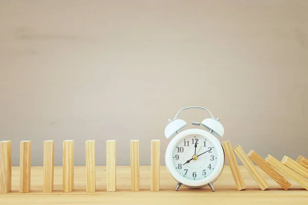 Un reloj deteniendo el efecto dominó. imagen de estilo retro ejecutivo y concepto de control de riesgos . —  Fotos de Stock