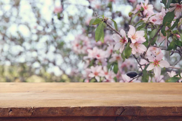 Dřevěný rustikální stůl před jarní Třešňové květy stromu. piknikové koše koncept a zobrazení produktů. — Stock fotografie